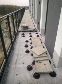 Balcon d'un bâtiment de bureaux recouvert par les dalles sur les plots - une finition durable, rapide et solide